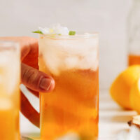 Hand reaching in to grab a glass of lemon ginger jasmine iced tea