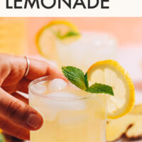 Hand reaching in to pick up a glass of refreshing ginger lemonade
