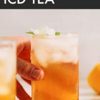 Hand reaching for a glass of jasmine ginger iced tea with text saying the recipe title above that