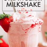 Glass of vegan and gluten-free creamy strawberry milkshake with vegan whipped cream on top