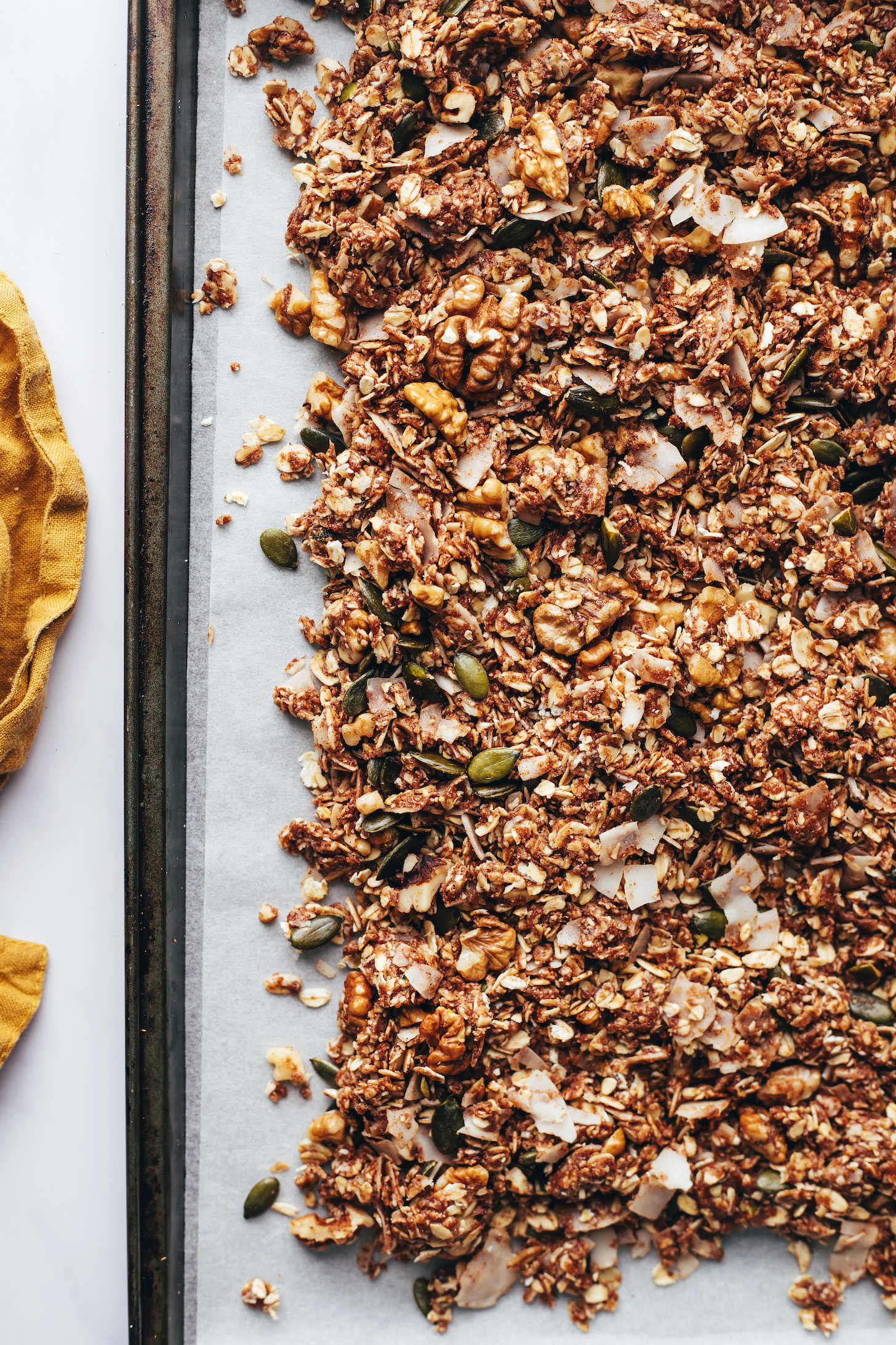 Baking sheet of chunky chai-spiced granola with pumpkin seeds and walnuts