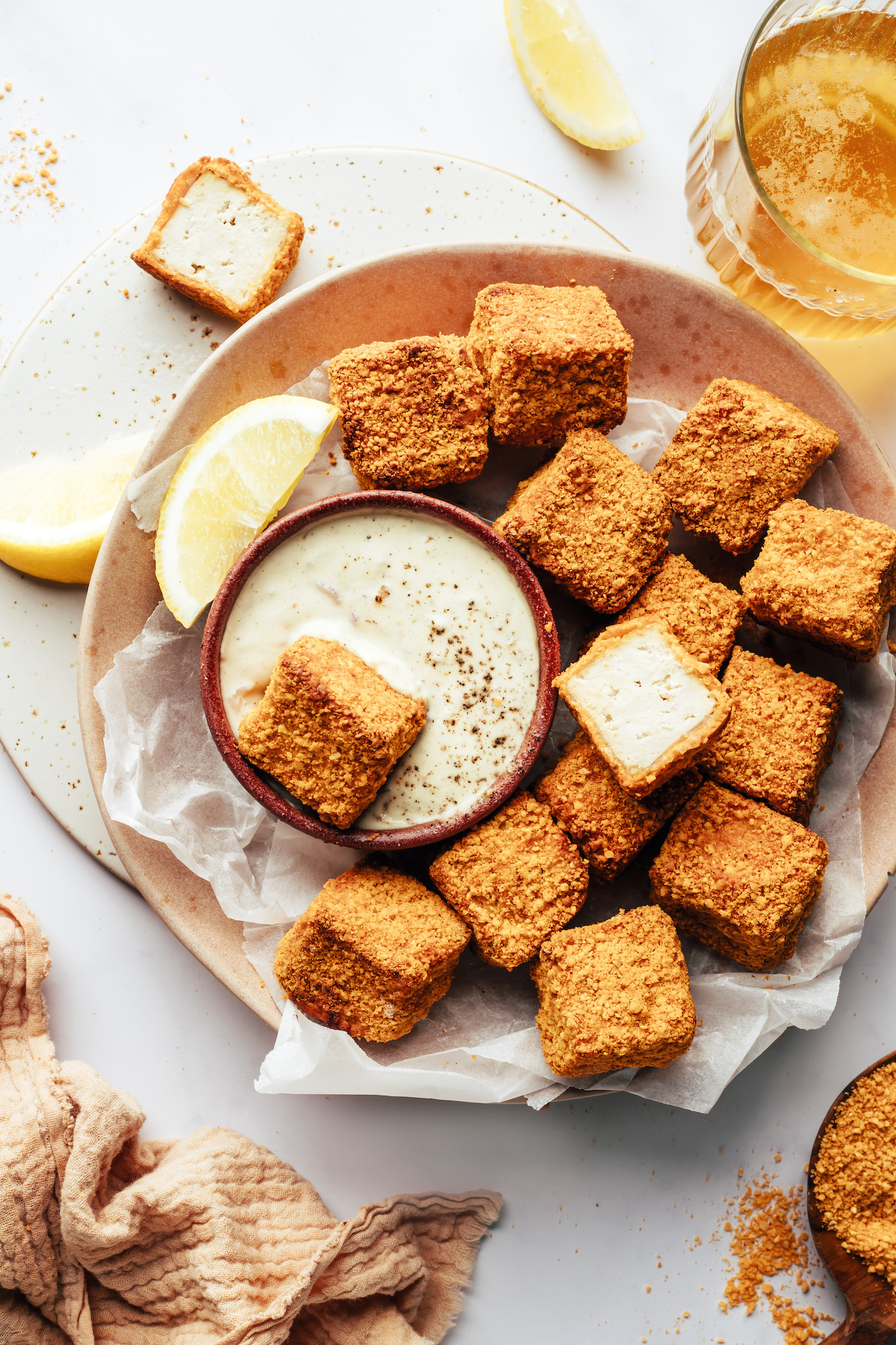 Plate of vegan "chicken" nuggets with one dipped in a bowl of vegan tartar sauce