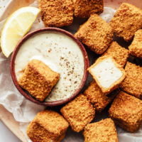 Bowl of vegan tartar sauce surrounded by tofu nuggets