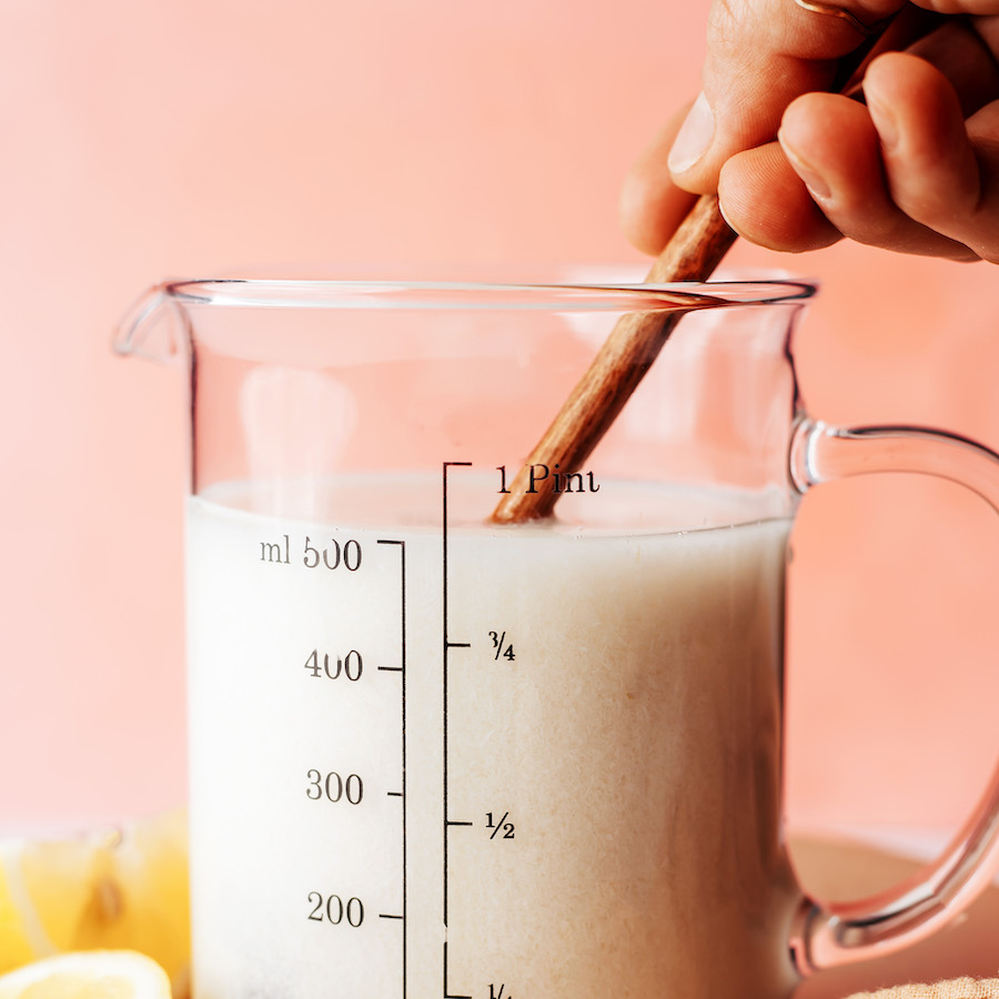 Rør mandelmælk og citronsaft i et måleglas for at lave vegansk kærnemælk
