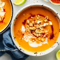Bowl of Instant Pot butternut squash soup topped with cashews, coconut milk, and sriracha