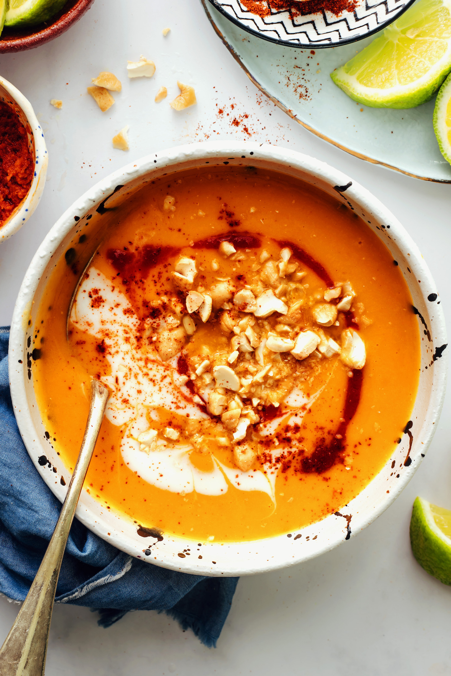 Bowl of spicy butternut squash soup topped with coconut milk, cashews, and sriracha