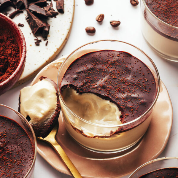 Spoonful of vegan tiramisu pudding next to a dessert cup