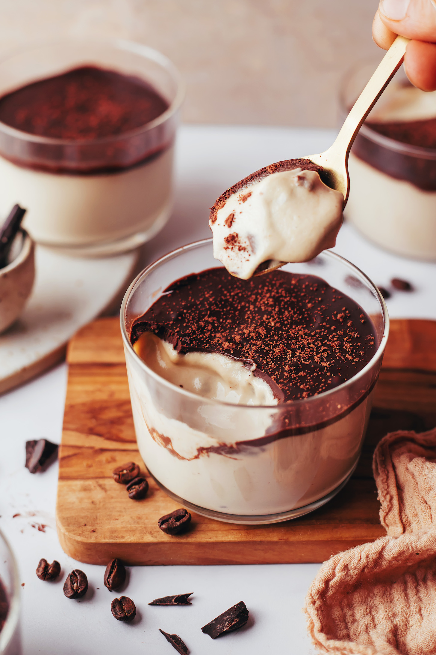 Holding a spoon of vegan tiramisu pudding over a dessert cup with more pudding