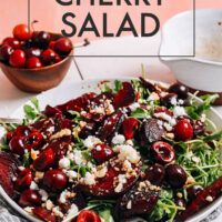 Vibrant beet, cherry, and arugula salad with text over the top saying Vegan & Gluten-Free Beet & Cherry Salad