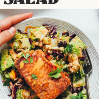 Hands holding a bowl of our Smoky Summer Salad with Lime-Crusted Salmon
