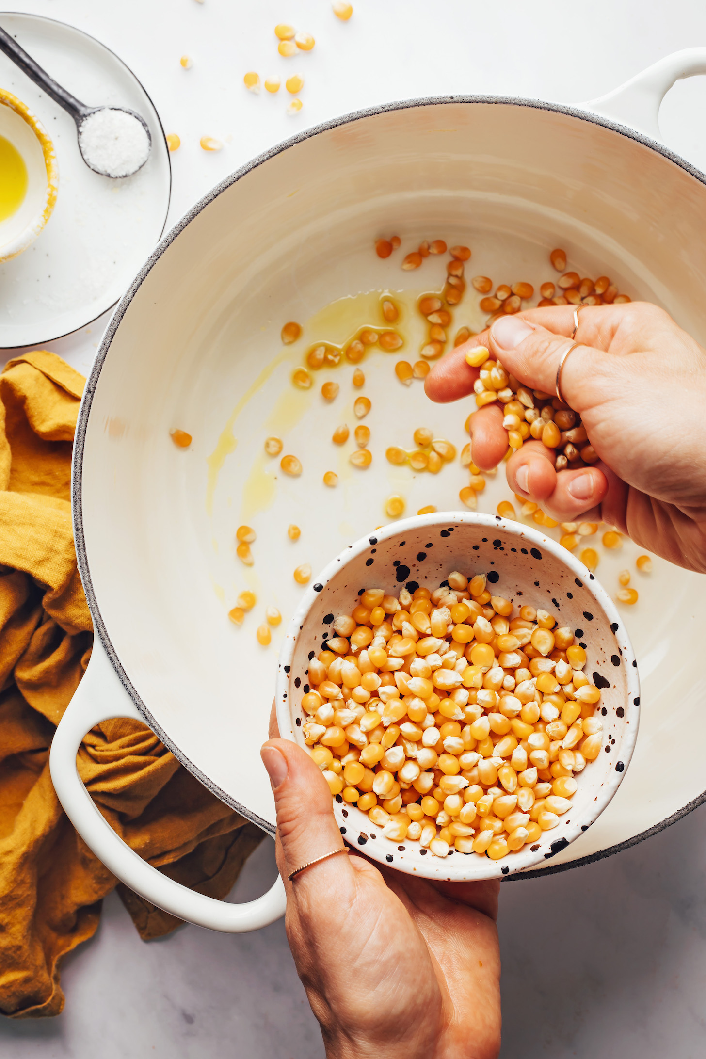 Adding dry popcorn kernels to a pot of warm oil