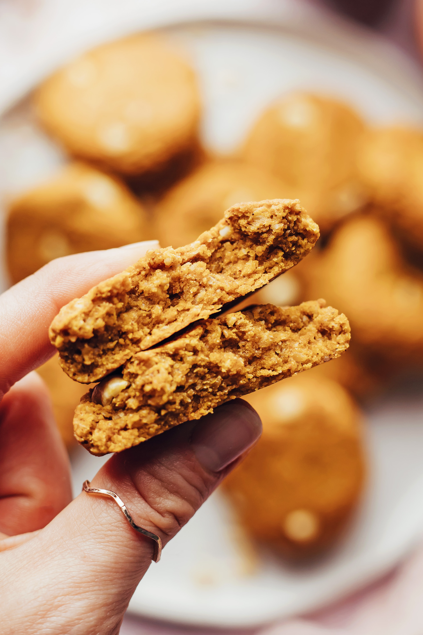 Immagine ravvicinata delle mani che tengono in mano un biscotto per la colazione con burro di arachidi e zucca