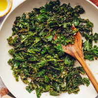Wooden spoon in a skillet of sautéed greens