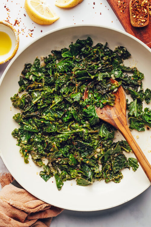 Wooden spoon in a skillet of sautéed greens