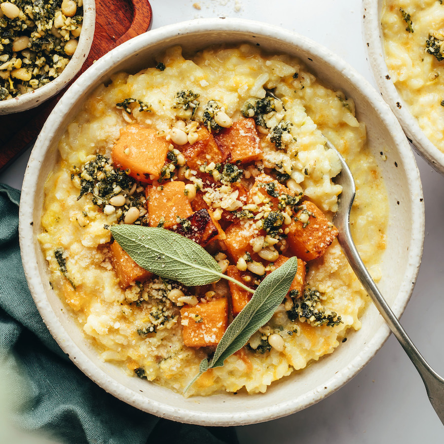 Spoon resting in a bowl of butternut squash risotto topped with pine nut sage gremolata