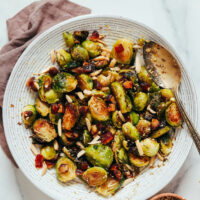 Bowl of crispy roasted brussels sprouts with toasted almonds, dates, and dukkah seasoning