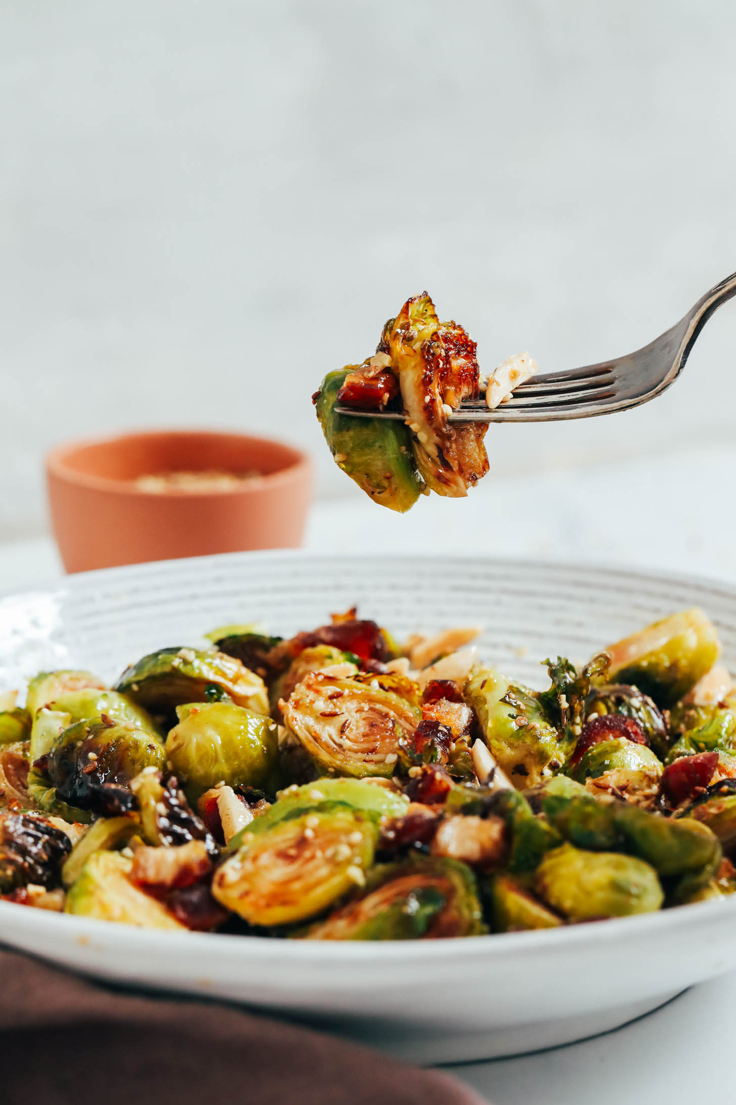Fork spearing a bite of roasted Brussels sprouts, toasted almonds, and dates