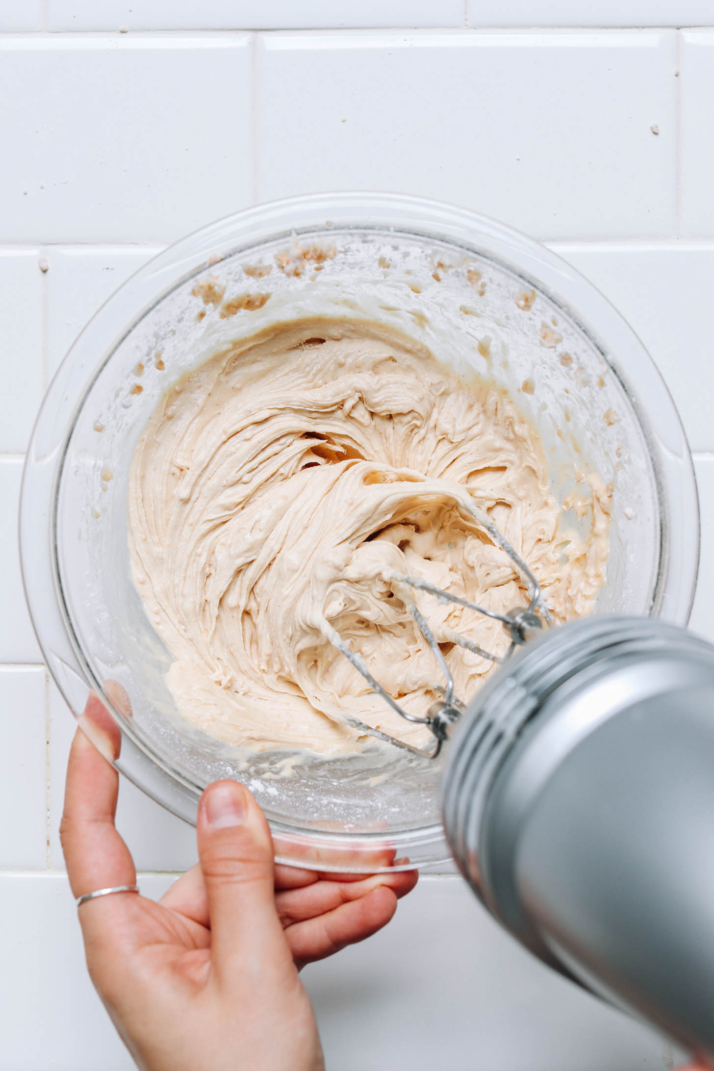 Verwenden Sie einen Handmixer, um ein flauschiges veganes Erdnussbutter-Frosting herzustellen