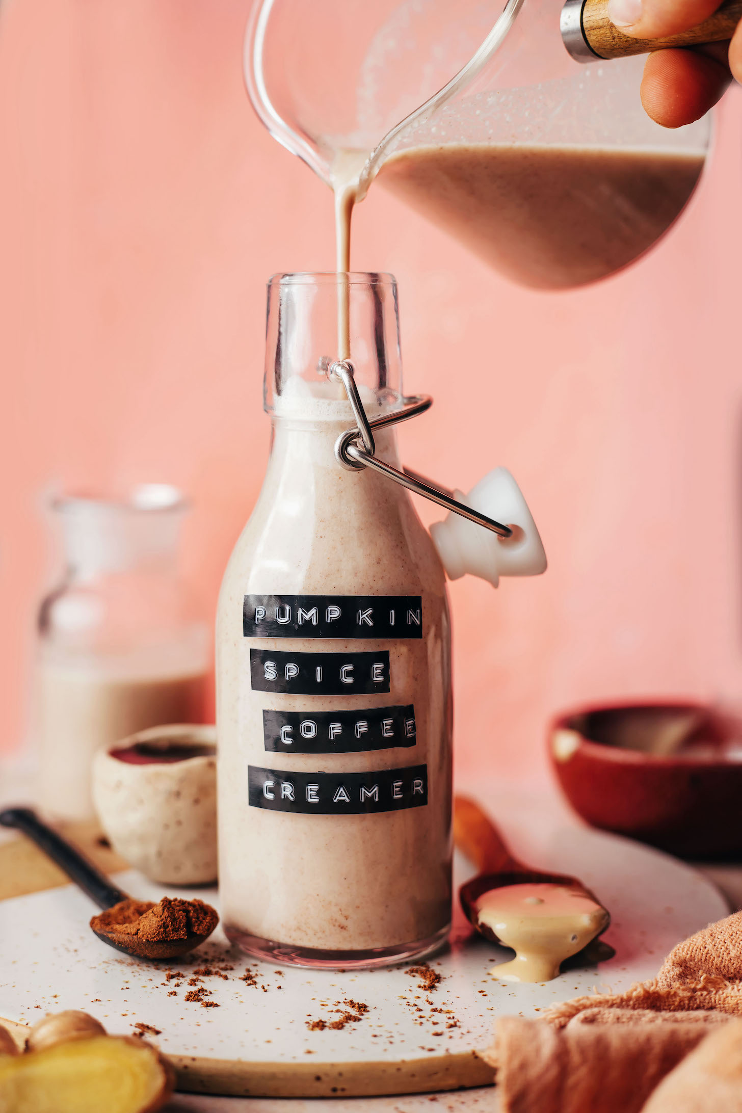 Pouring dairy-free pumpkin spice coffee creamer into a small bottle