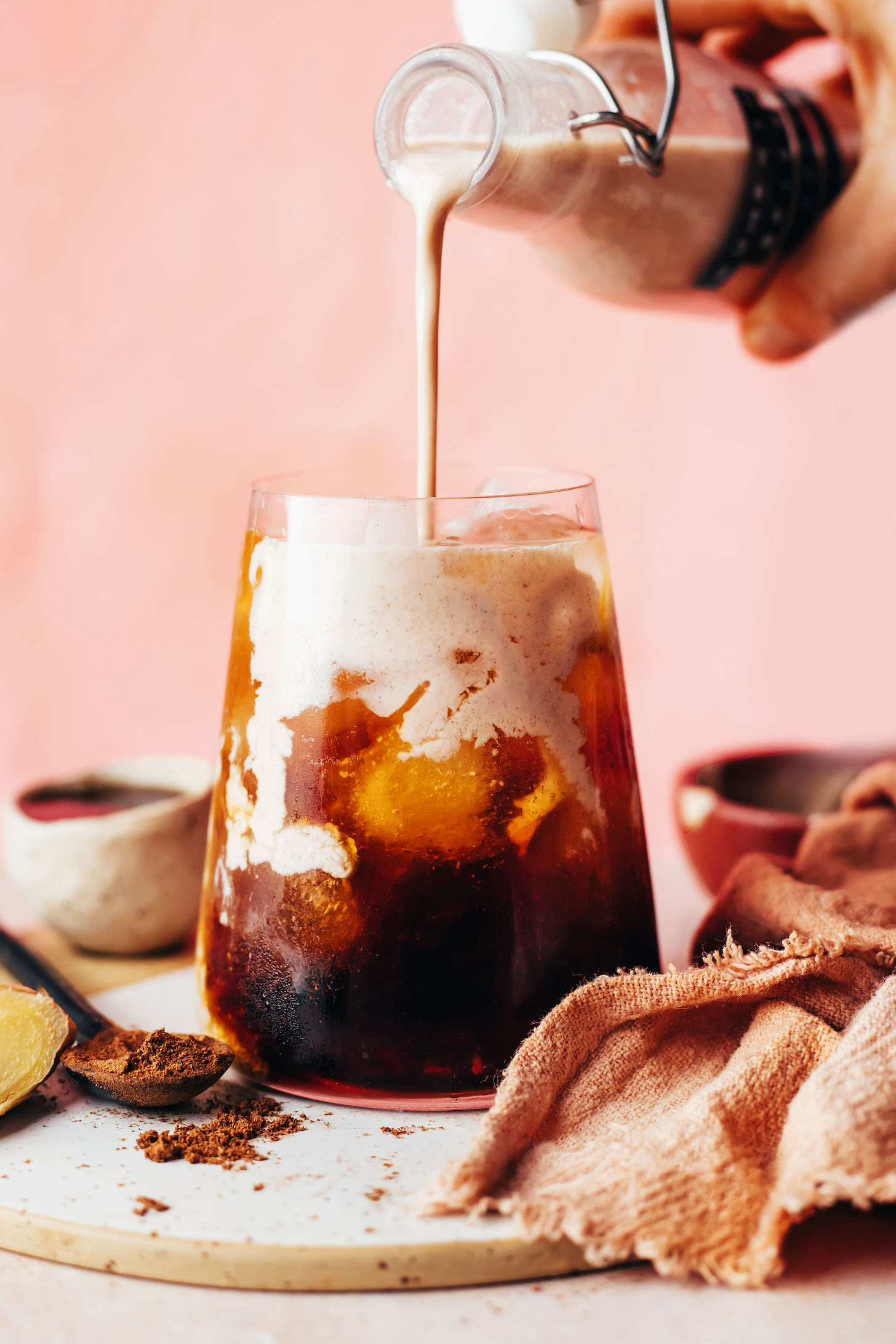 Kürbisgewürz-Kaffeesahne in ein Glas Eiskaffee gießen