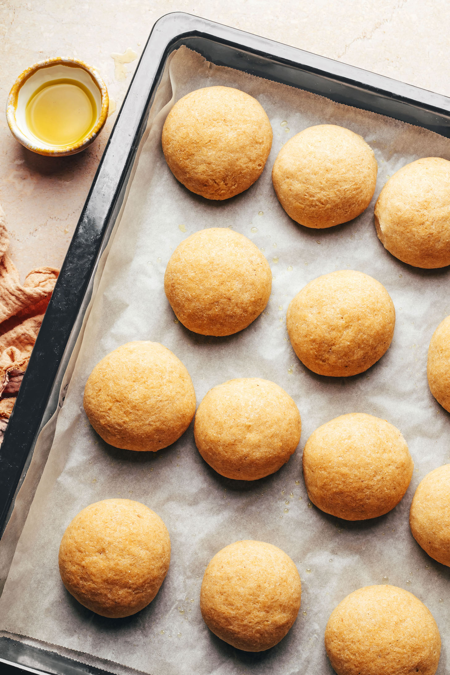 Freshly baked gluten-free vegan dinner rolls on a baking tray lined with baking paper
