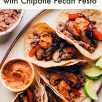 Platter of gluten-free tacos with fajita veggies, refried beans, and chipotle pecan pesto