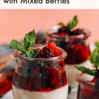 Small jars of vegan panna cotta topped with a mixed berry compote