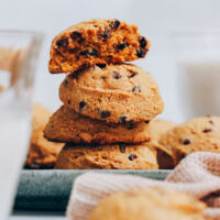 Stack of pumpkin chocolate chip cookies next to a glass of dairy-free milk