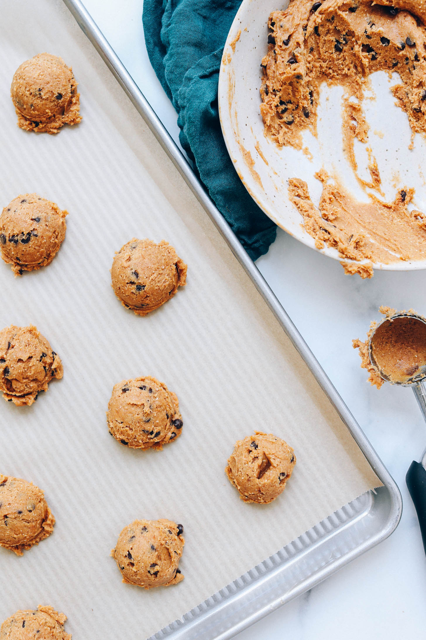 Pumpkin chocolate chip cookie dough in a bowl and in mounds on a baking sheet