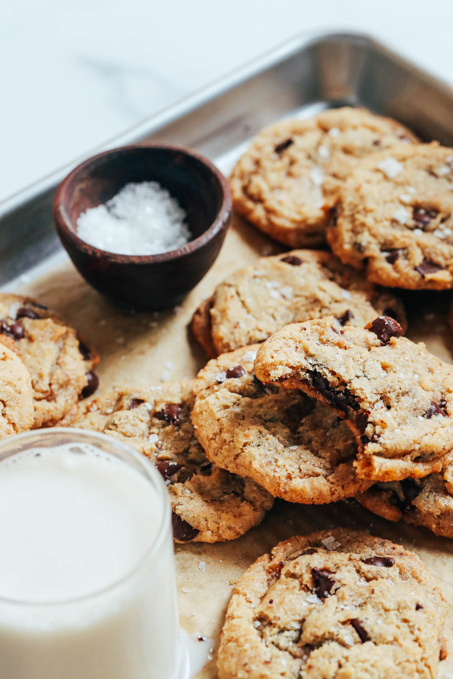 Flaky salt and dairy-free milk on a baking sheet of vegan gluten-free chocolate chip cookies