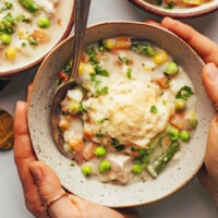 Hands cradling a bowl of gluten-free chicken pot pie soup