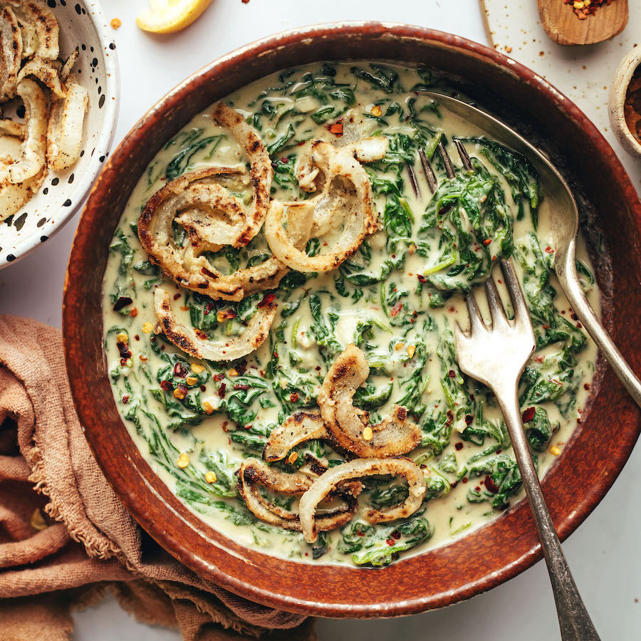 Bowl of vegan creamed spinach topped with crispy fried onions
