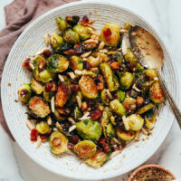 Spoon in a bowl of crispy roasted Brussels sprouts with almonds, dates, and dukkah seasoning