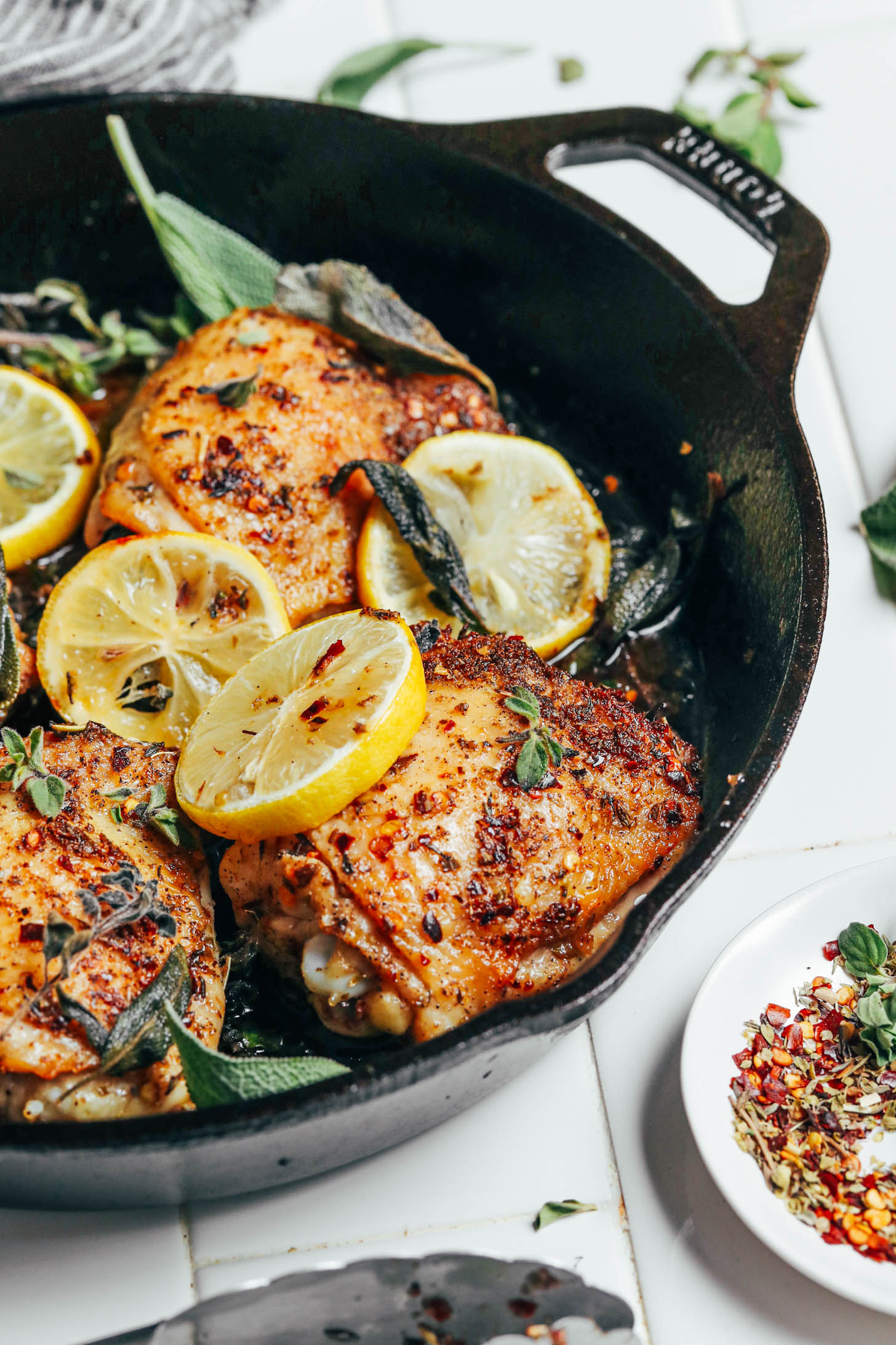Golden brown roasted chicken thighs in a pan with lemon and herbs