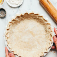 Hands holding a pie pan filled with our gluten free pie crust recipe