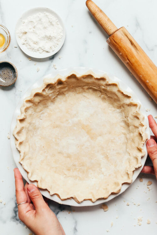 Hands holding a pie pan filled with our gluten free pie crust recipe