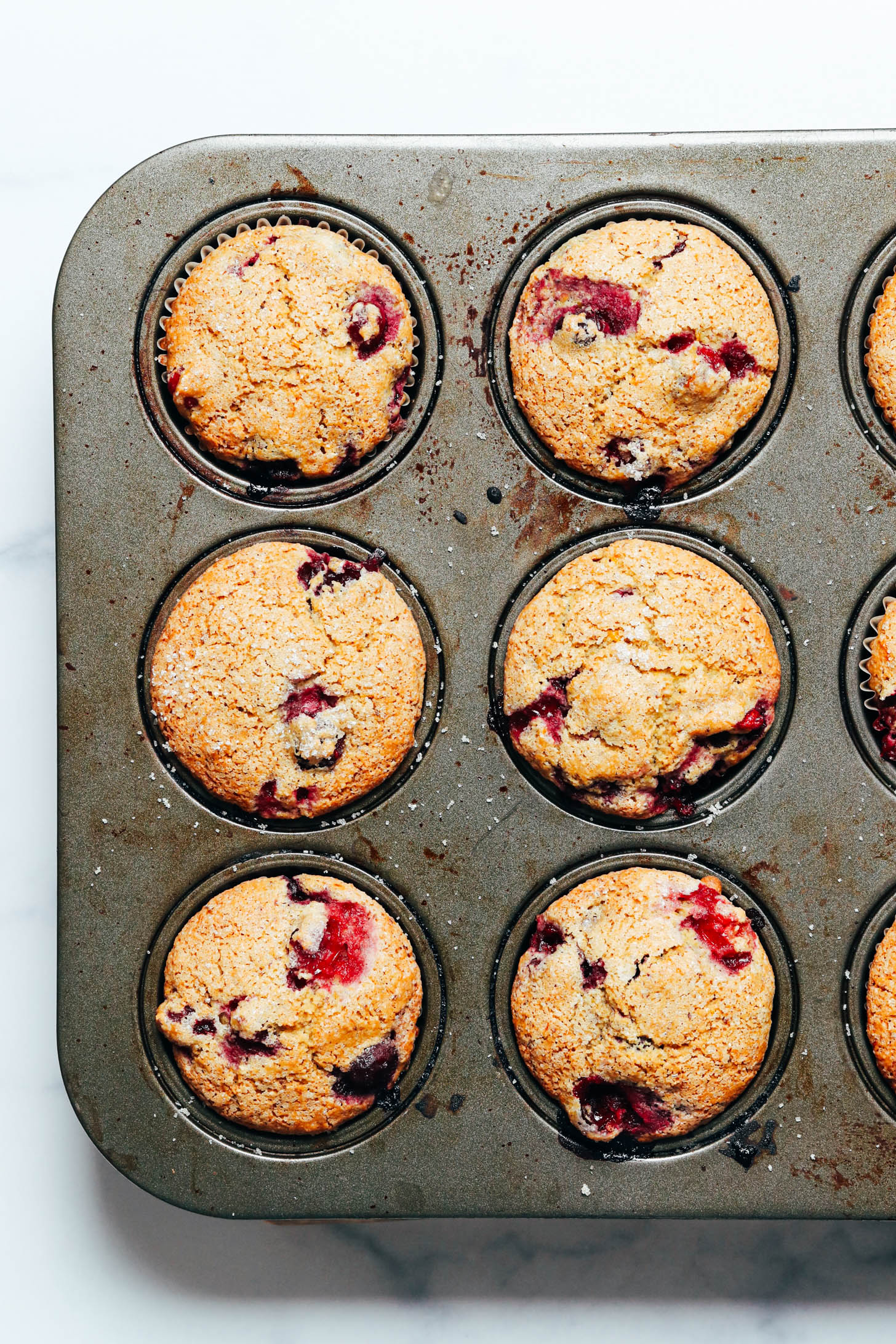 Top down shot of freshly baked vegan gluten free cranberry orange muffins in a muffin tin