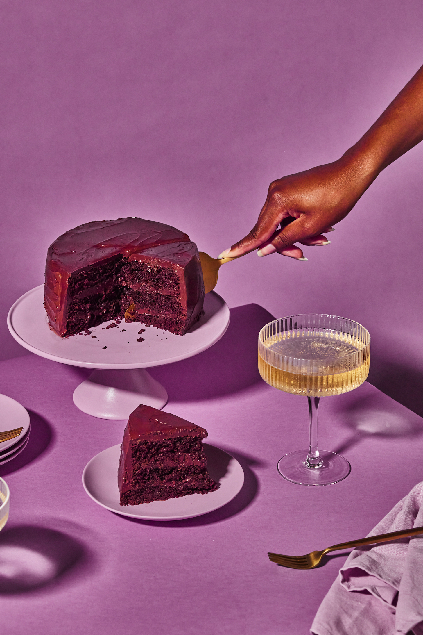 Menggunakan penghiris kek emas untuk dipotong menjadi kepingan vegan yang gebu dan kek coklat bebas gluten