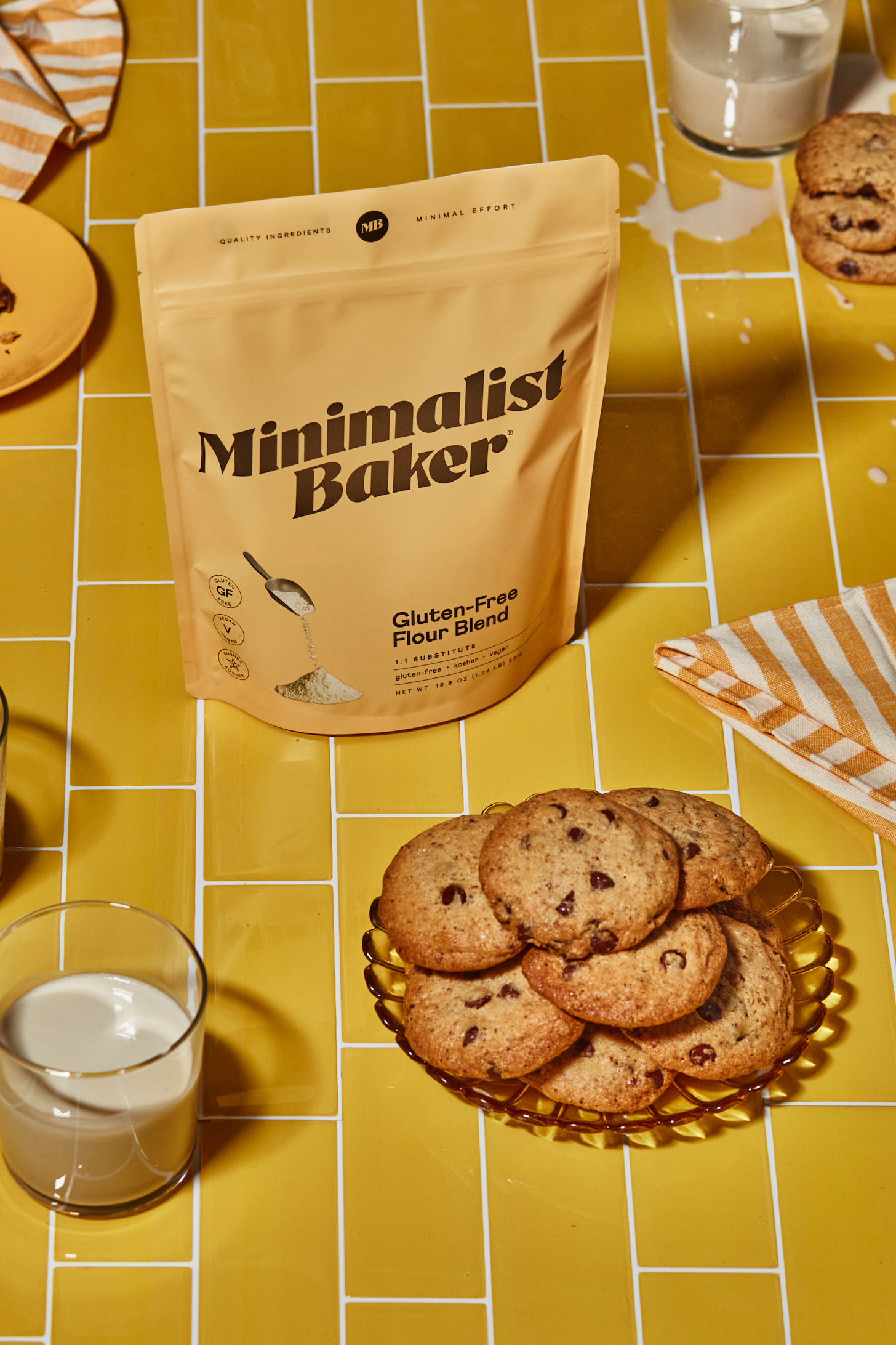 Bag of our amazing gluten-free flour blend next to a plate of chocolate chip cookies and dairy-free milk