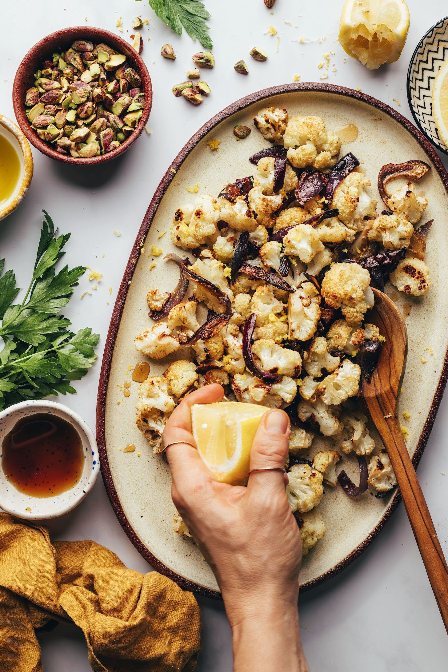 Squeezing lemon juice over roasted cauliflower and red onion