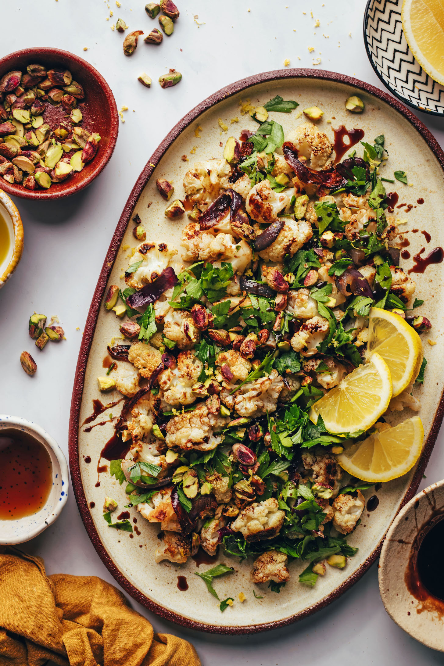 Pistachios and lemon slices next to a platter of our roasted cauliflower salad recipe