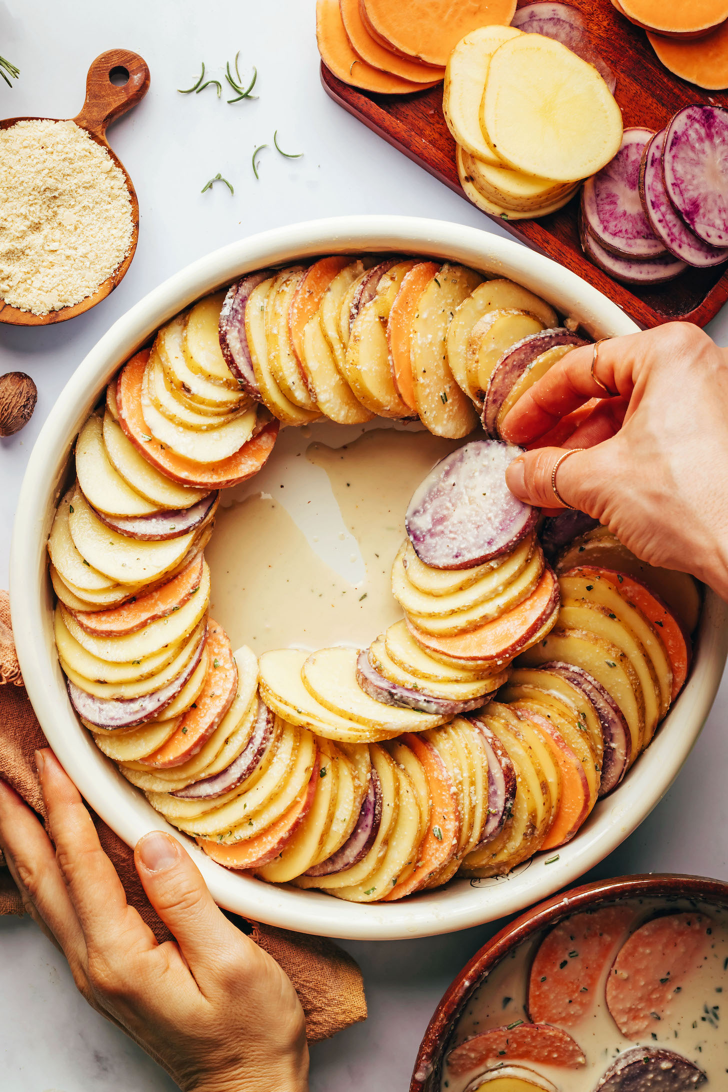 Placing potatoes into a circular pan in a spiral pattern