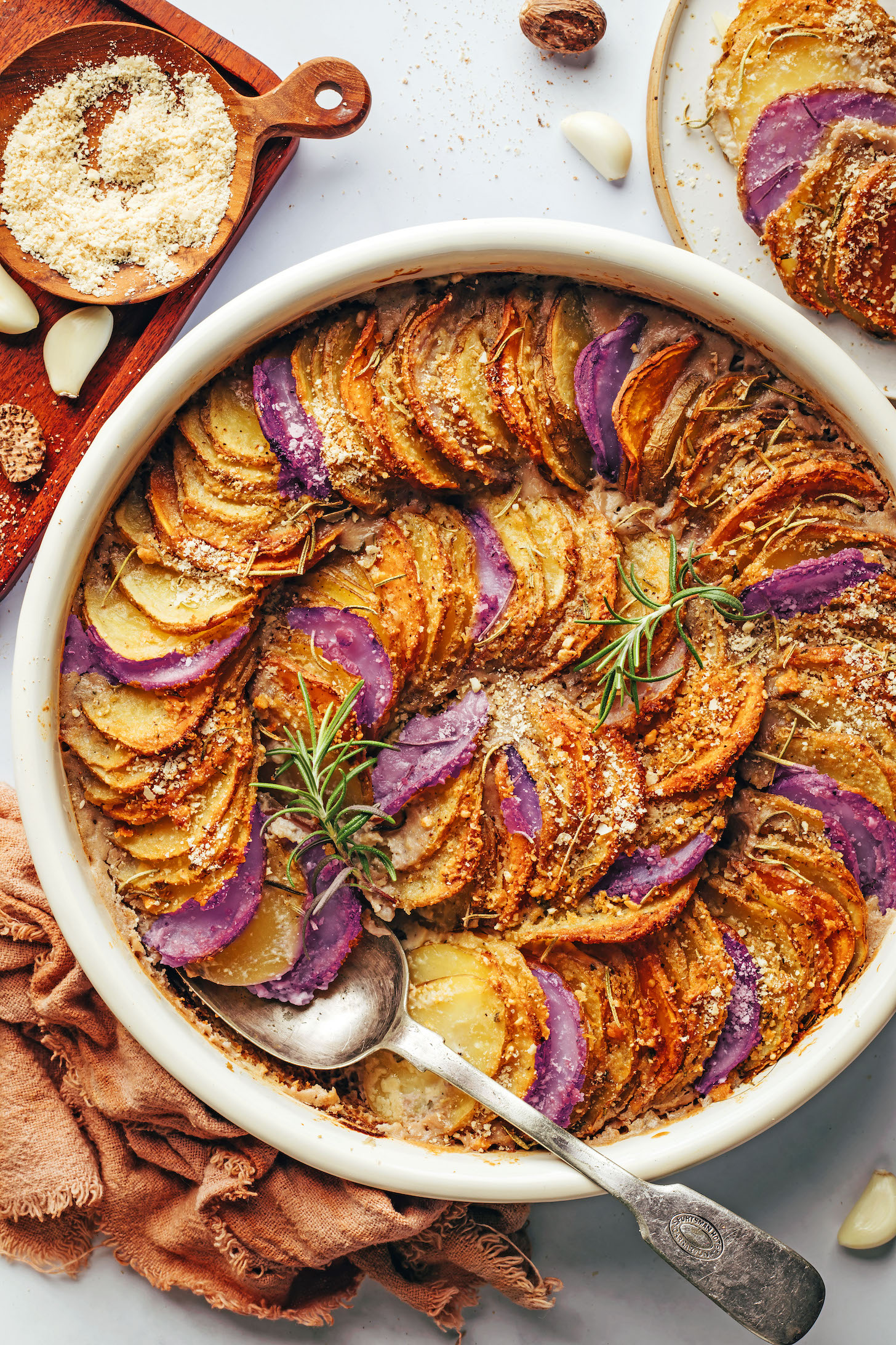 Circular baking dish filled with a vegan potato gratin arranged in a circular pattern