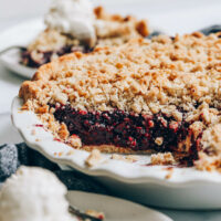 Slice of mixed berry pie next to a pie pan with the rest of it