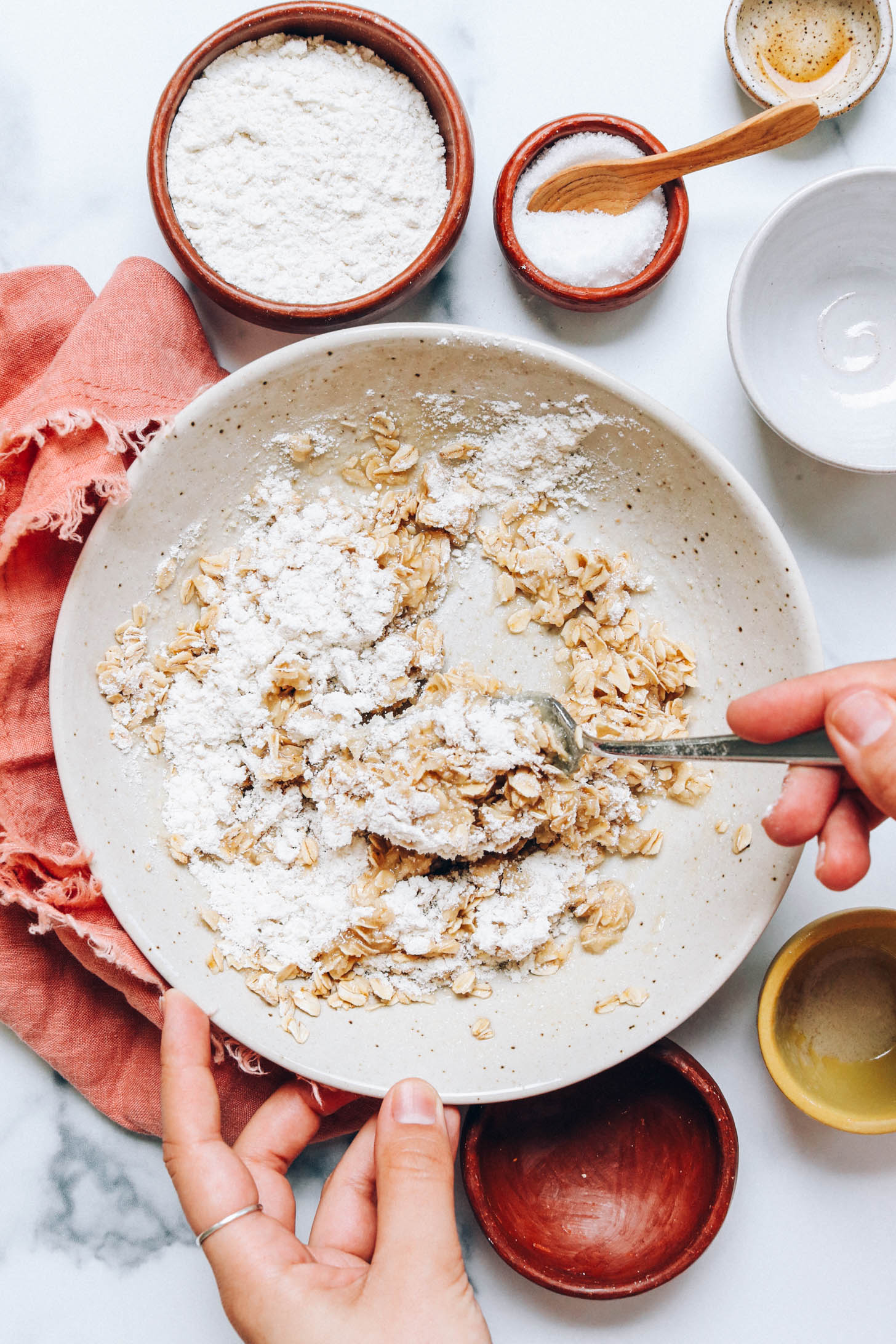 Stirring oats, gluten-free flour, vegan butter, vanilla, salt, and sugar to make a crumble topping