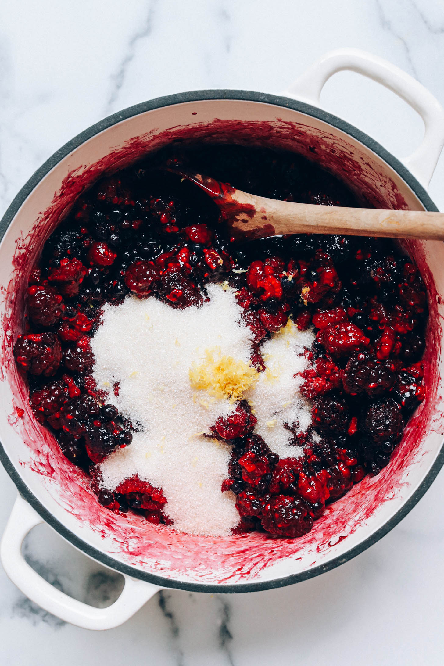 Sugar and lemon zest in a pan of saucy mixed berries