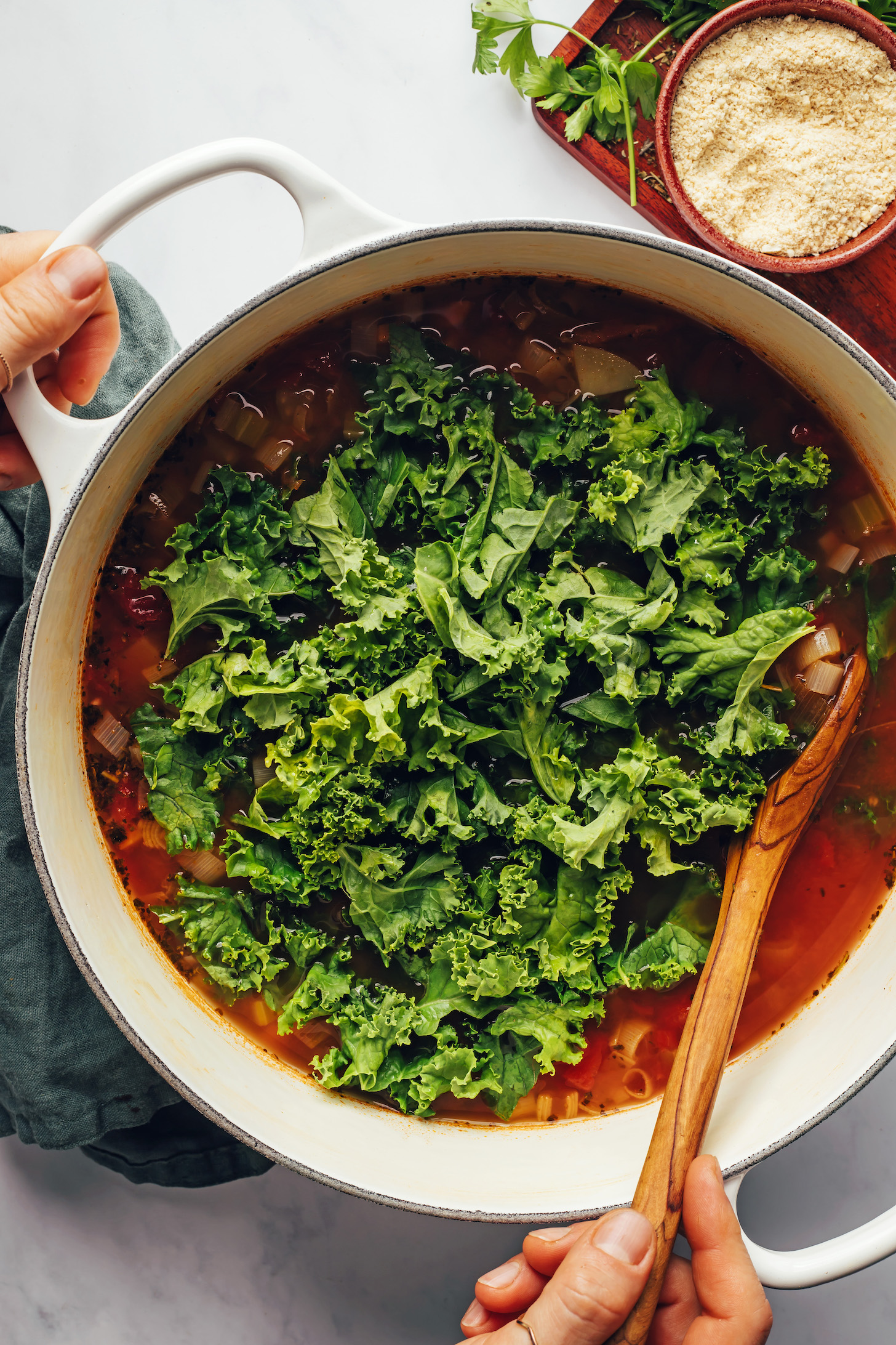 Rühren Sie frisch gehackten Grünkohl in einen Topf Suppe
