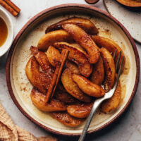 Cinnamon stick over a plate of caramelized cinnamon-spiced pears
