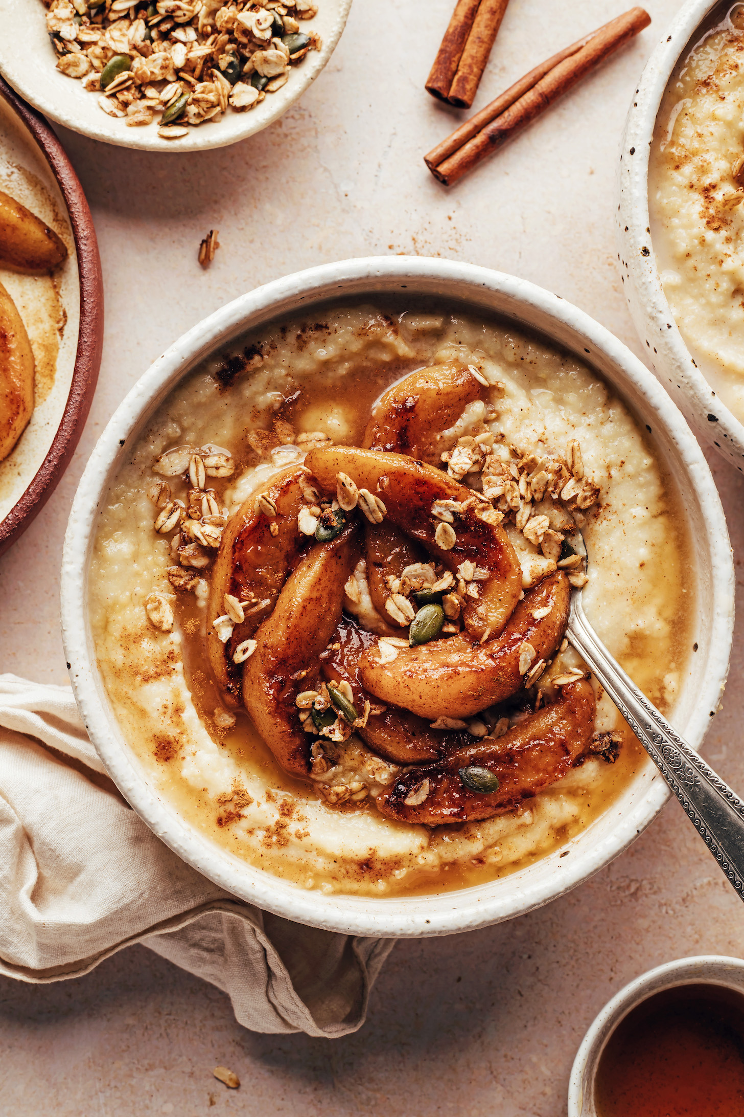 Overhead shot of a bowl of creamy millet porridge with cinnamon-spiced pears and granola