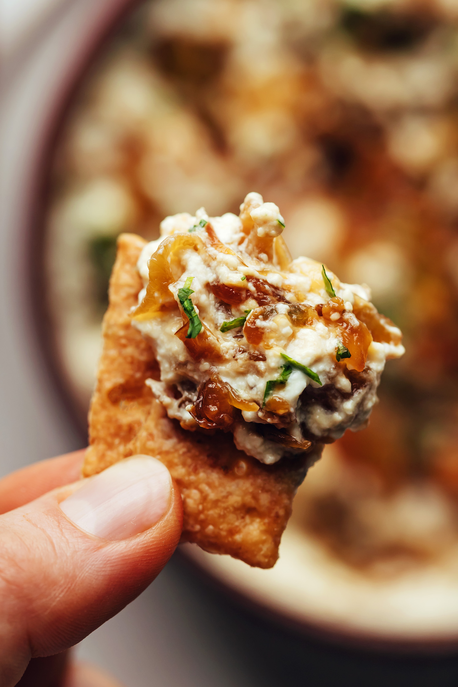 Holding up a cracker topped with caramelized onion dip